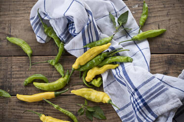 Gelbe und grüne Chilis (Paprika), Peperoni, mit Blättern auf dem Tisch - ASF06563