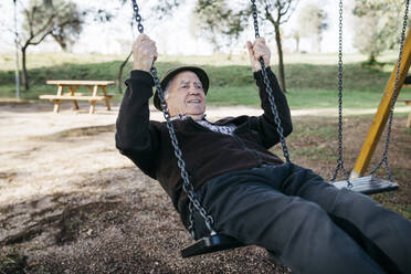 Alter Mann schaukelt auf einem Spielplatz im Park - JRFF04119