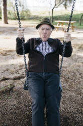 Old man swinging on playground in park - JRFF04120