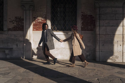Junges Paar, das Hand in Hand in der Stadt Venedig, Italien, spazieren geht - MAUF03244