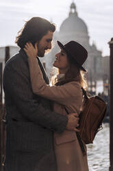 Affectionate young couple at the waterfront in Venice, Italy - MAUF03274