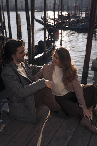 Junges Paar sitzt am Ufer in Venedig, Italien, lizenzfreies Stockfoto