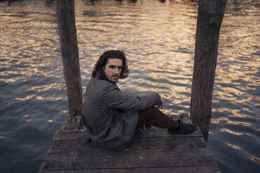Junger Mann sitzt am Ufer in Venedig, Italien - MAUF03291