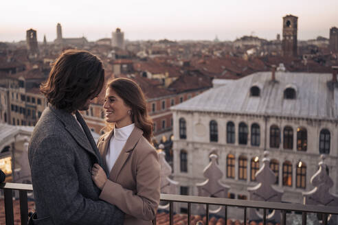 Glückliches junges Paar auf einem Balkon über der Stadt Venedig, Italien - MAUF03308