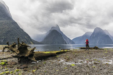 Neuseeland, Ozeanien, Südinsel, Südland, Fiordland National Park, Frau steht am Milford Sound, Mitre Peak im Hintergrund - FOF11775