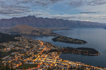New Zealand, Otago, Queenstown, Town on shore of Lake Wakatipu at dusk with mountains in background - FOF11809