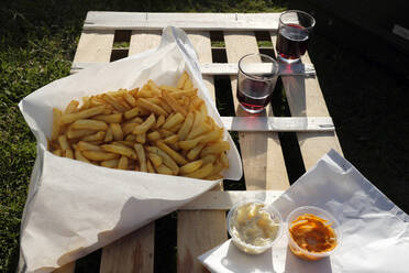 Frankreich, Bretagne, Audierne, Pommes frites mit Mayonnaise, Ketchup und Rotwein - Picknick auf Holzkiste - GISF00509