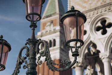 Italien, Venedig, Verschnörkelte Straßenlaterne mit Markusdom im Hintergrund - MAUF03317