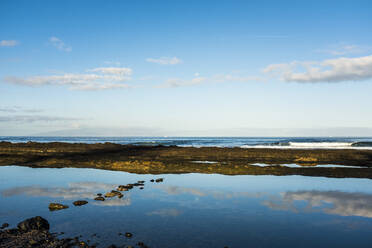 Spain, Canary Islands, Tenerife, Clouds reflecting in large puddle on coastal beach - SIPF02134