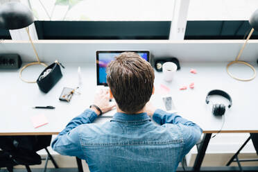 Hoher Blickwinkel eines Geschäftsmannes, der einen Laptop benutzt, während er am Schreibtisch im Büro sitzt - MASF16317