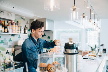 Junger Besitzer macht Kaffee an der Kasse im Büro-Café - MASF16332