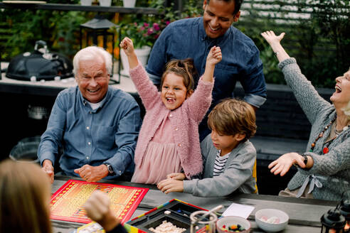 Fröhliche Mehr-Generationen-Familie beim Brettspiel auf dem Tisch im Innenhof - MASF16462