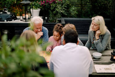 Mehrgenerationenfamilie beim Brettspiel auf dem Tisch, während sie auf der Terrasse sitzt - MASF16464