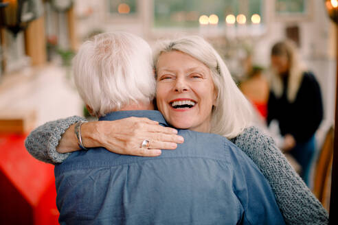 Porträt einer älteren Frau, die einen Mann umarmt, während sie zu Hause steht - MASF16467