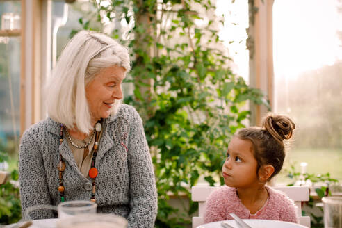 Lächelnde Großmutter sieht ihre Enkelin beim Mittagessen an - MASF16475