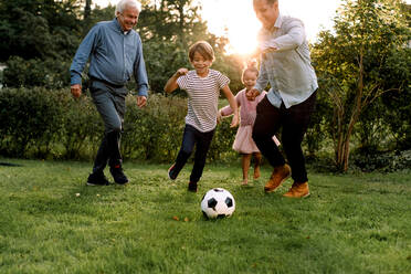 Mehrgenerationen-Familie in voller Länge beim Fußballspielen im Hinterhof - MASF16481