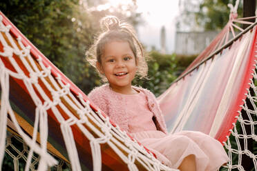 Porträt eines lächelnden Mädchens, das in einer Hängematte im Hinterhof sitzt - MASF16494