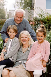 Portrait of grandparents and grandchildren sitting in backyard - MASF16496