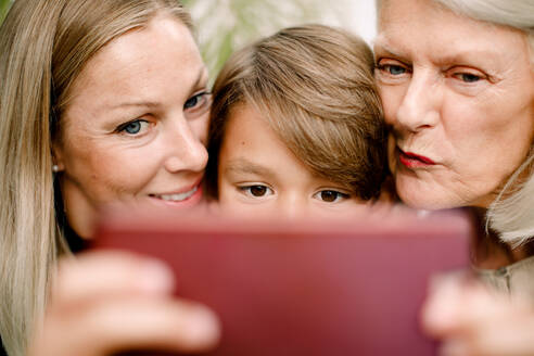 Nahaufnahme einer Mehrgenerationenfamilie, die ein Selfie mit einem Mobiltelefon macht - MASF16500