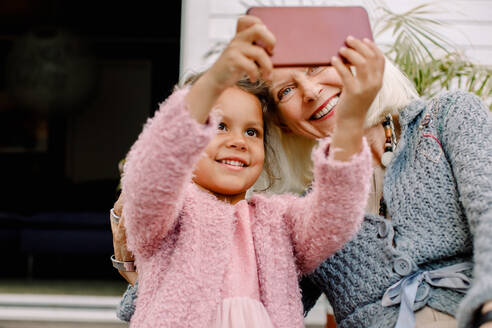 Lächelnde Enkelin und Großmutter machen ein Selfie mit dem Handy - MASF16502