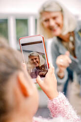 Granddaughter taking photograph of grandmother in mobile phone - MASF16503