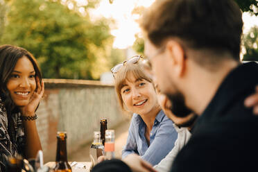 Lächelnde Frauen sitzen bei männlichen Freunden auf einer Gartenparty - MASF16524