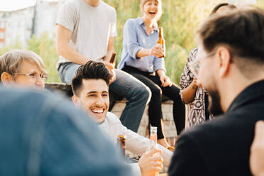 Männliche und weibliche Freunde lachen bei einer Gartenparty und halten Bier in der Hand - MASF16537