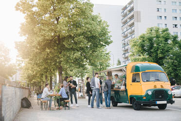 Male and female customers standing by food truck - MASF16555