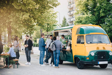 Male and female customers standing by food truck - MASF16557