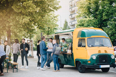 Male and female customers standing by food truck - MASF16558