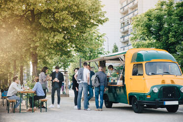 Male and female customers standing by food truck - MASF16559