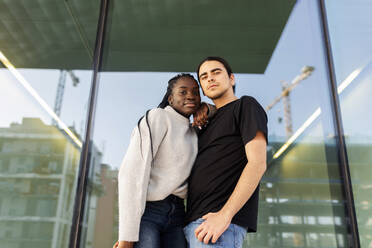 Portrait of a confident young couple standing at a glass front - VABF02614