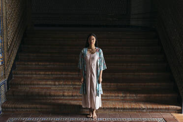 Porträt einer schönen jungen Frau in einem Kimono auf einer Treppe stehend - TCEF00157