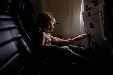 Kleines Mädchen im Flugzeug hält Hände mit Schwester im anderen Gang - CAVF74291