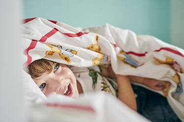 Kleinkind versteckt sich unter einer Decke im Zimmer - CUF54667