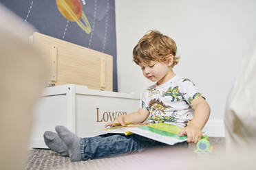 Toddler reading book in room - CUF54673