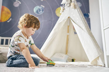 Toddler playing in room, child's teepee, mural of solar system on wall - CUF54676