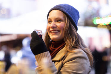 Frau hält kleines Glas mit Getränk, Weihnachtsmarkt, Freiburg, Deutschland - CUF54693