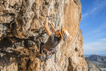 Woman climbing at rock face - DLTSF00454