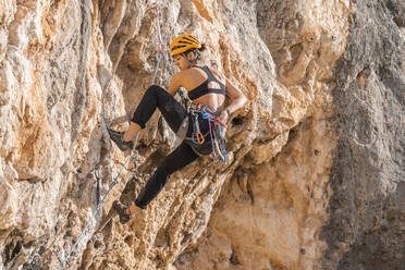 Woman climbing at rock face - DLTSF00457