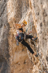 Woman climbing at rock face - DLTSF00458