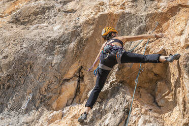 Woman climbing at rock face - DLTSF00459