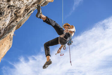 Female climber abseiling from rock face - DLTSF00460