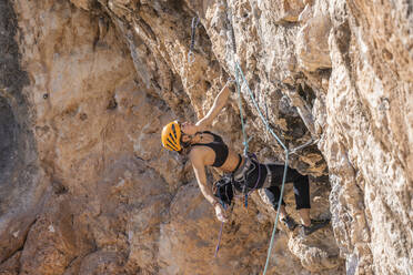 Woman climbing at rock face - DLTSF00467