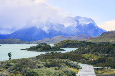 Chile, Provinz Ultima Esperanza, Männlicher Rucksacktourist beim Wandern entlang des Ufers des Pehoe-Sees mit den Cuernos del Paine im Hintergrund - LOMF01008