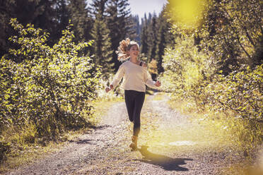 Girl running and jumping on a forest path, having fun - DHEF00117