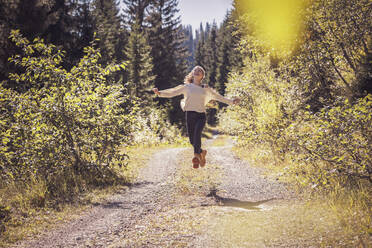 Girl running and jumping on a forest path, having fun - DHEF00118