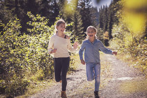 Mädchen laufen und haben Spaß auf einem Waldweg in der Natur - DHEF00122