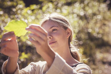 Curious girl, looking at autmn leave, smiling - DHEF00123