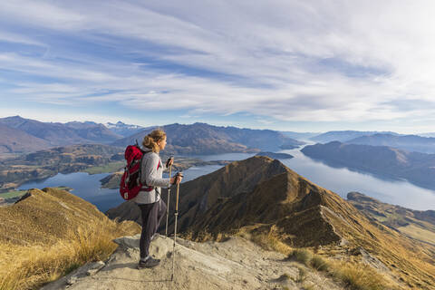 Frau steht auf einem Aussichtspunkt am Roys Peak und blickt zum Mount Aspiring, Lake Wanaka, Südinsel, Neuseeland, lizenzfreies Stockfoto